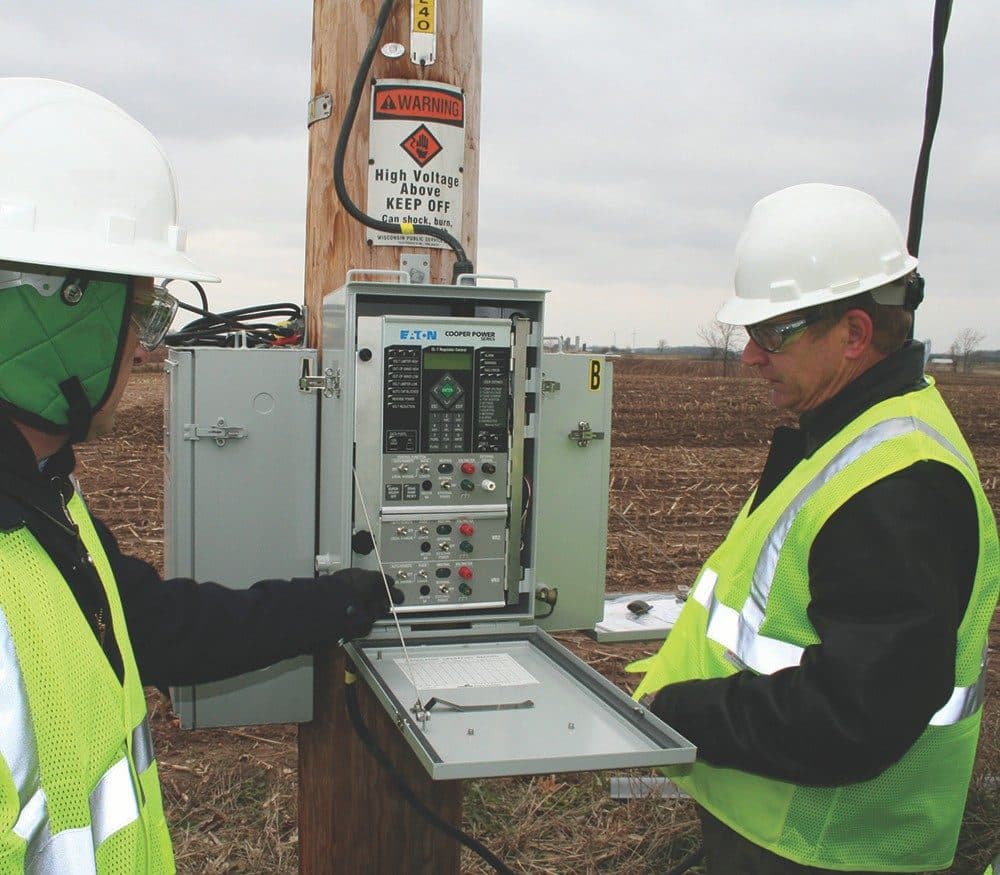 Lineworkers operating a regulator control on a pole