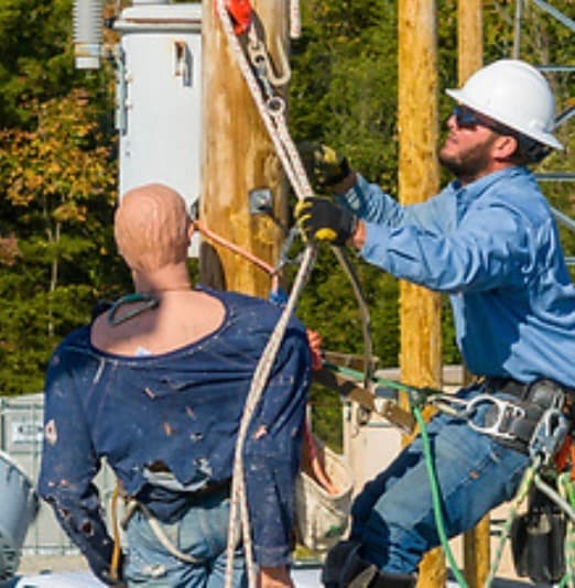 Lineworker performing a pole top rescue with a training dummy